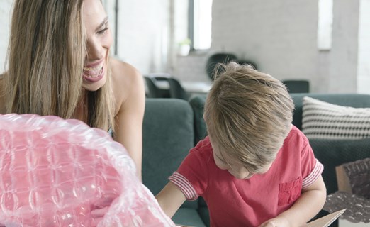 Mother happily opening package with son containing package protected by Inspire Pink Protective Packaging