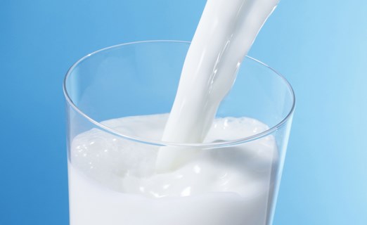 Pouring milk in glass with blue background