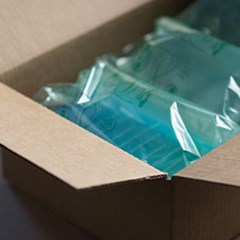 Green recycled air pillow packaging used as void fill inside box.