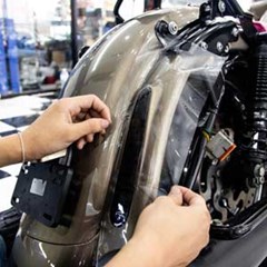 Removable adhesive film being applied to a motorcycle for paint surface protection.